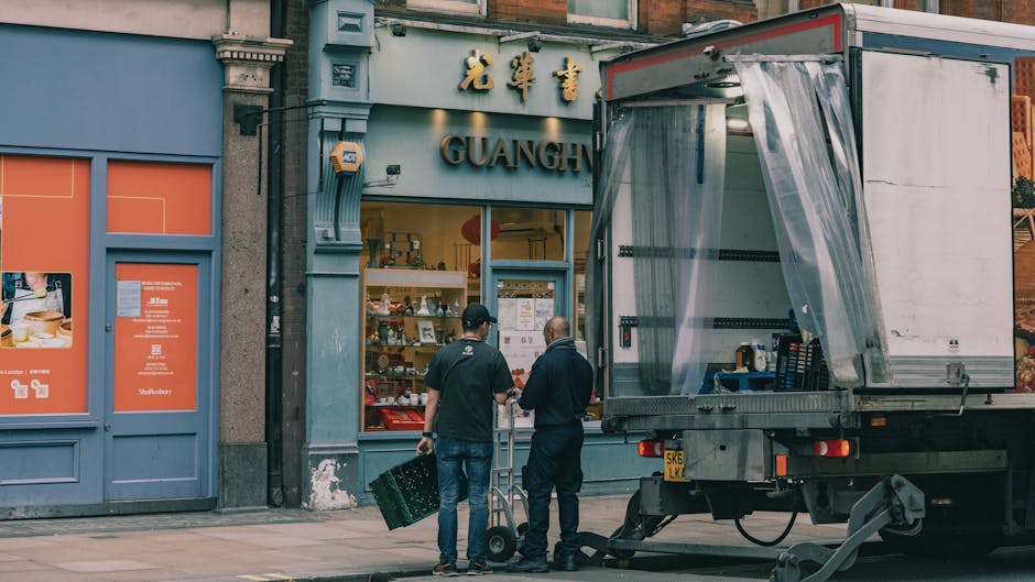 The image shows a section of a storage area or shopfront with a large wooden display cabinet containing various supplies, including plastic containers, tins, and small boxes, all arranged on glass she